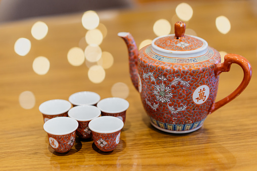 Red porcelain teapot and cups on table for tea ceremony in Chinese wedding