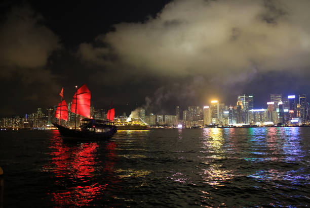 Chinese red junk with the victoria harbor night view background in hong kong stock photo