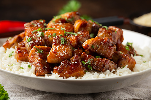 Chinese traditional cuisine sticky braised pork belly with rice on white plate.