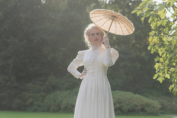 Chique Victorian Woman With Parasol Walking In Garden Stock Photo