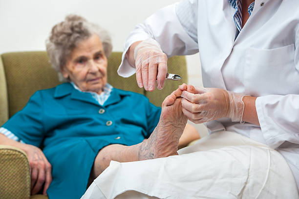 Chiropody Nurse assists an elderly woman with chiropody and body care at home pedicure stock pictures, royalty-free photos & images