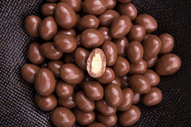 Chocolate ball candy smarties on black background with nuts inside stock photo