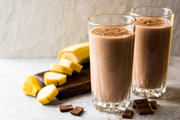 Chocolate banana smoothie in glass on gray stone background stock photo