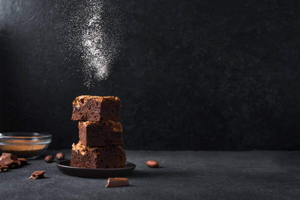 Chocolate brownie dessert Stack of  brownies on black background. Delicious homemade chocolate dessert, brownie with sugar powder,  copy space. brownie stock pictures, royalty-free photos & images