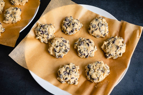 Chocolate Chip Cookie Dough on a Parchment Lined Plate Raw cookie dough on a parchment paper-lined plate semi sweet chocolate stock pictures, royalty-free photos & images