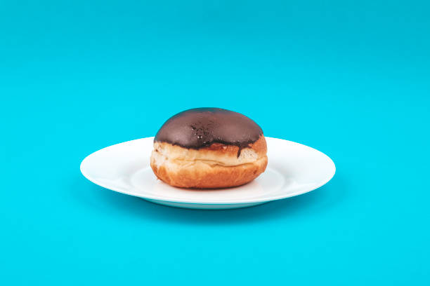 Chocolate donut on a white plate on a blue background Chocolate donut on a white plate on a blue background lepro stock pictures, royalty-free photos & images