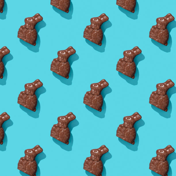 Chocolate Easter Bunny on blue background pattern, flat lay stock photo