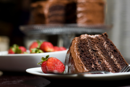 Close up of a piece of chocolate layer cake with strawberries.