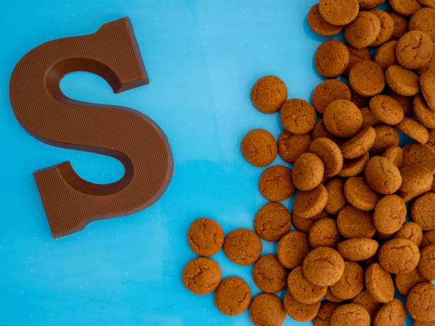 chocolade letter s en dutch candy genaamd pepernoten voor het feest van sinterklaas op een blauwe achtergrond. - kruidnoten stockfoto's en -beelden