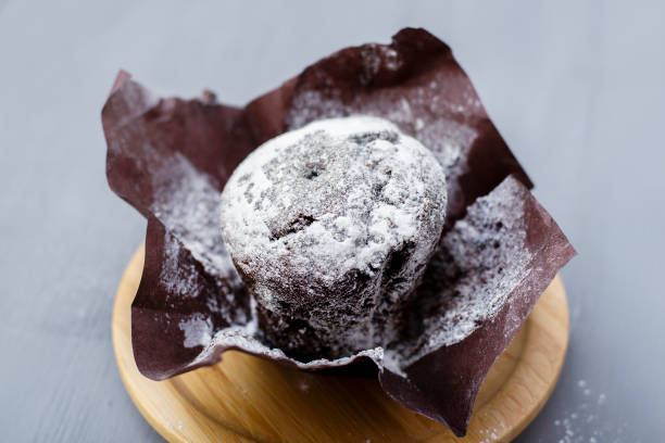 Chocolate muffin with powdered sugar on top on a light background. stock photo