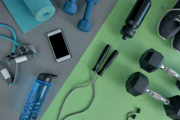 High angle shot of a variety of workout equipment laid out on a green exercise mat before a workout