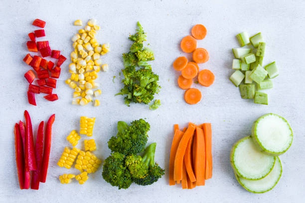 Chopped vegetables on the white background, carrot, broccoli, corn and bell pepper stock photo