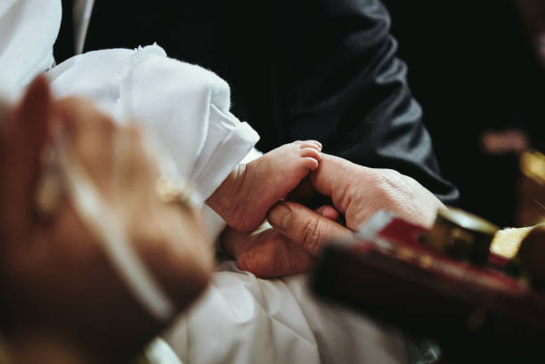 christening of little baby in church, close-up feet and priest hand stock photo