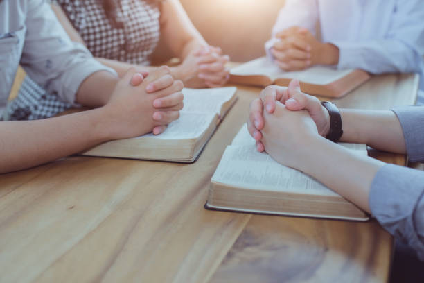 Christian small group studying the bible and pray together on wooden table in homeroom. stock photo