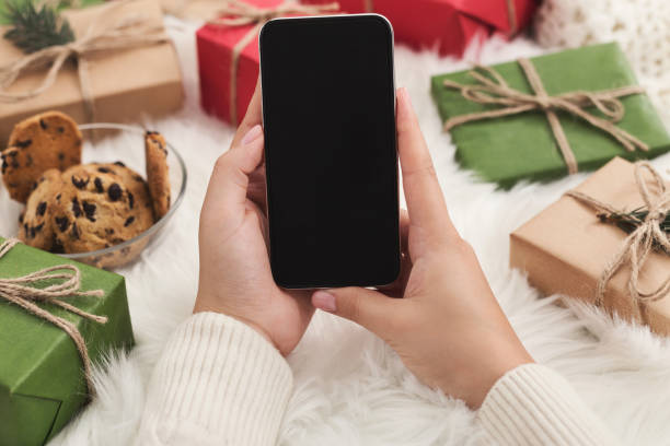 christmas application. woman using smartphone mockup, copy space - woman holding a christmas gift imagens e fotografias de stock