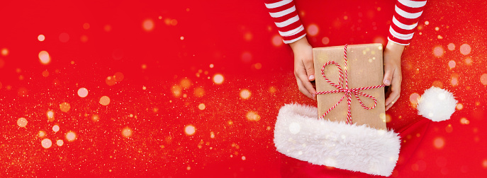 Christmas banner gift box in children's hands on a red background, presenting a gift