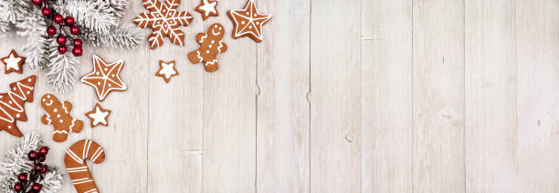 Christmas corner border of gingerbread cookies and frosty tree branches. Above view on a grey wood banner background. stock photo