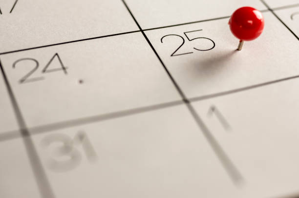 Christmas day marked on calendar Close up shot of a red pin on the 25th day on calendar holiday calendars stock pictures, royalty-free photos & images