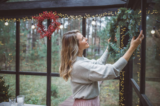 Christmas during self-isolation period Mature women celebrating Christmas alone during hers coronavirus self-isolation period. She is decorating space for Christmas evening. greenhouse table stock pictures, royalty-free photos & images