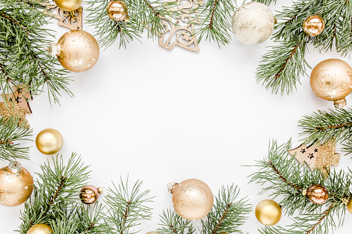 Christmas frame, pattern made in gold colors and and gold glass Christmas balls on white background with empty copy space for text. Holiday and celebration concept. Top view. Flat lay.