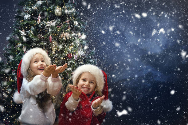 christmas funny kids catching snow in hands. happy children on winter holiday vacation playing outside. snowfall. xmas eve night - christmas magic imagens e fotografias de stock