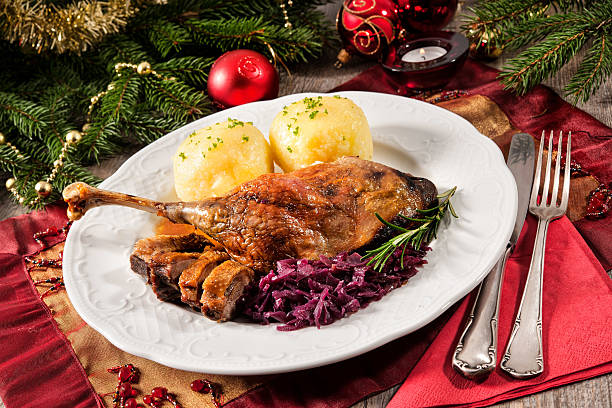 Christmas goose Crusty goose leg with braised red cabbage and dumplings on Christmas decorated table goose meat photos stock pictures, royalty-free photos & images