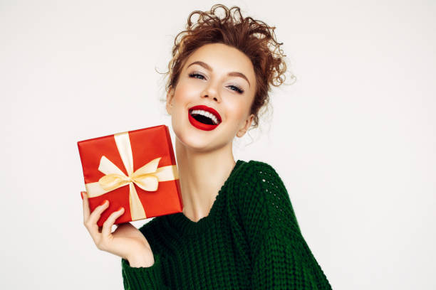 christmas happy smiling young woman holds gift box in hands - woman holding a christmas gift imagens e fotografias de stock