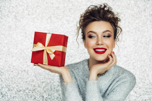 christmas happy smiling young woman holds gift box in hands - woman holding a christmas gift imagens e fotografias de stock