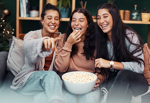 Shot of young sisters having popcorn and watching tv together during Christmas at home