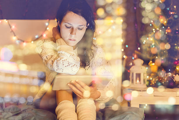 Christmas Girl using digital tablet at home new years eve girl stock pictures, royalty-free photos & images