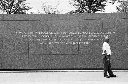 Washington DC, USA - June 13, 2012: An African-American man stands beside a quote at the Martin Luther King Jr Memorial in Washington DC. The quote is from a 1967 Christmas sermon in Atlanta, Georgia and reads: 