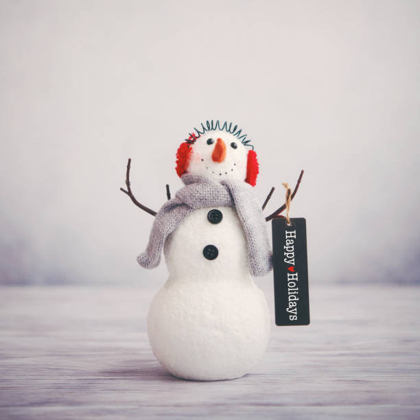 bodegón de navidad con lindo muñeco de nieve sosteniendo felicitaciones felices vacaciones - happy holidays fotografías e imágenes de stock