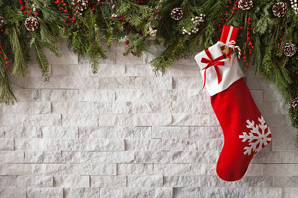 Christmas Stocking Christmas Stocking with gifts and bow hung on a fireplace with evergreen garland. christmas stocking stock pictures, royalty-free photos & images