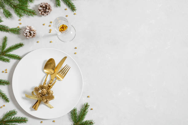 Christmas table setting with golden cutlery and fir branches on a gray background. View from above. Space for text. stock photo