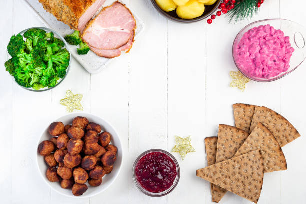 Christmas table with baked ham, beet salad, whole grane crackers, meatballs with lingonberry jam stock photo