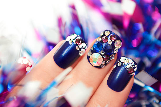 Christmas winter blue manicure . Christmas winter blue manicure with rhinestones of different shapes and sparkles of snow on female hand with a garland. artificial nail stock pictures, royalty-free photos & images