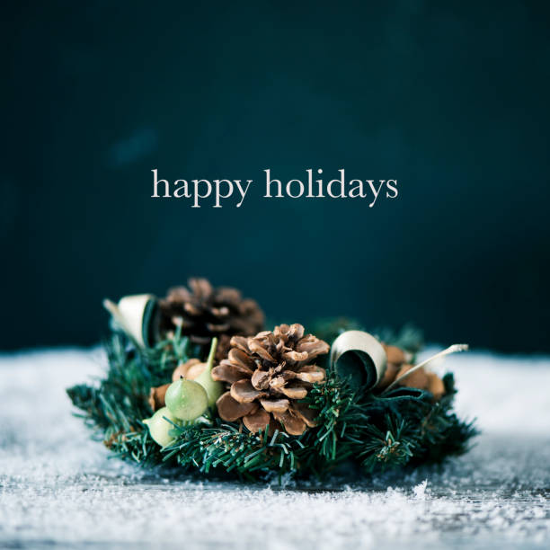christmas wreath and text happy holidays a christmas wreath, made with pinecones and other leaves, on the snow and the text happy holidays happy holidays stock pictures, royalty-free photos & images