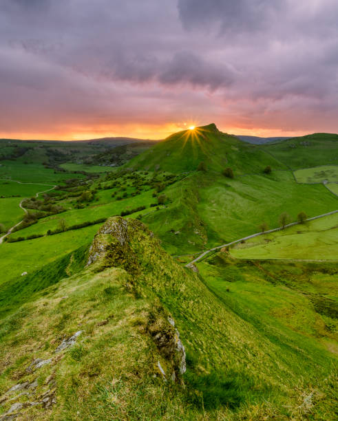 Chrome Hill At Sunset. Sun shining brightly as it sets below horizon at sunset with Chrome Hill in the background. Taken in the Peak District National Park, UK. peak district national park stock pictures, royalty-free photos & images