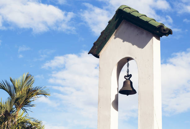 Church bell on church tower on blue sky background. Catholic church building. Church bell on church tower on blue sky background. Catholic church building. Catholic religious architecture detail. White stone tower with bell. Traditional religious building on tropical island bell tower tower stock pictures, royalty-free photos & images