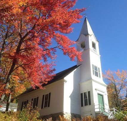 Leaves turning on a tree by a New England church.