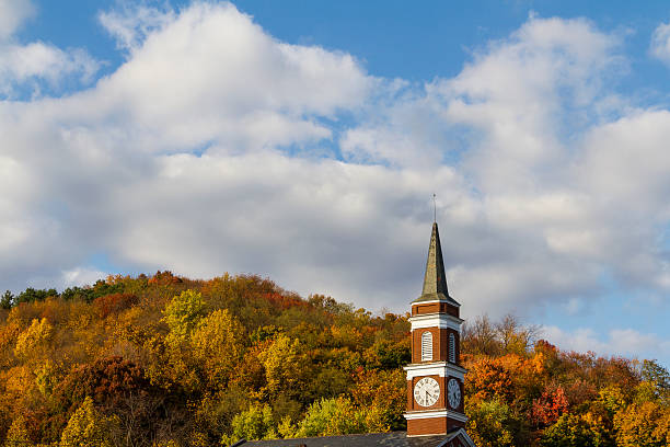 Church Steeple Against Autumn Colors "An autumn view of a church steeple, hillside of autumn colors and a bright blue sky with fluffy white clouds." cumberland river stock pictures, royalty-free photos & images