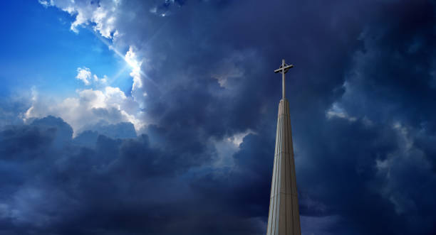 Church tower with religious cross over dramatic cloudy sky stock photo