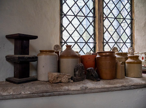 A church windowsill cluttered with a selection of pots and old pieces of broken statuary. Church of St Mary the Virgin in Sedgeford, Norfolk, Eastern England.