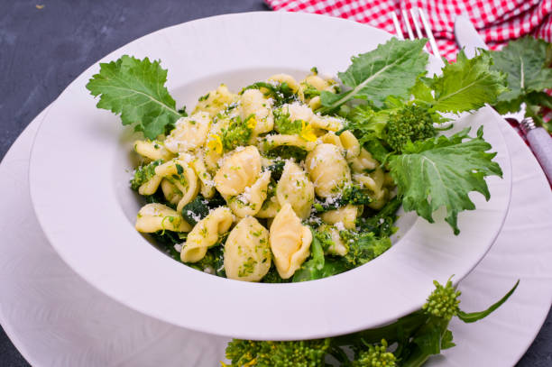 Cime di rapa pasta in a plate on with parmesan on table. Traditional food of the south of Italy, from Puglia. Rustic style photo. Copy space  broccoli rabe stock pictures, royalty-free photos & images