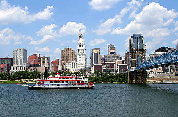 Cincinnati Skyline with Replica Steamboat in Ohio River. Replica steamboat travels down the Ohio River in front of the Cincinnati skyline. cincinnati stock pictures, royalty-free photos & images