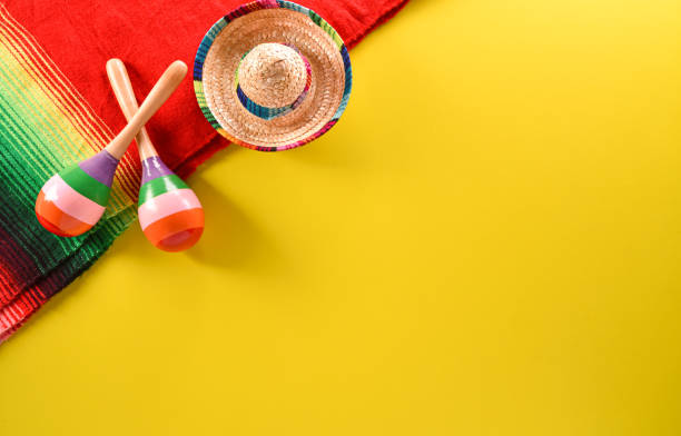 Cinco de Mayo holiday background made from maracas, mexican blanket stripes or poncho serape and hat on yellow background. stock photo