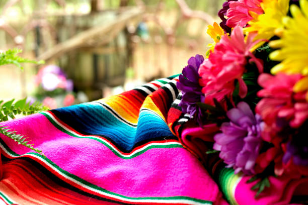 Cinco de Mayo table setting with serape, pace setting and flowers on an outdoor picnic table.