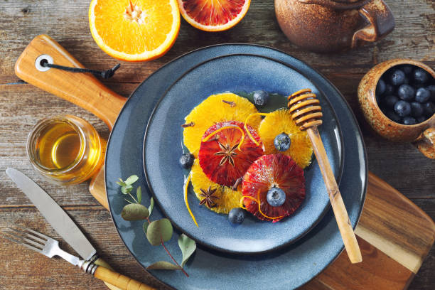 Citrus dessert. Orange carpaccio with honey, spices and blueberries from yellow and blood oranges stock photo