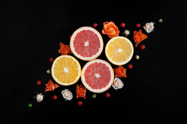Citruses and flowers. Orange, grapefruit and roses. Black background. stock photo