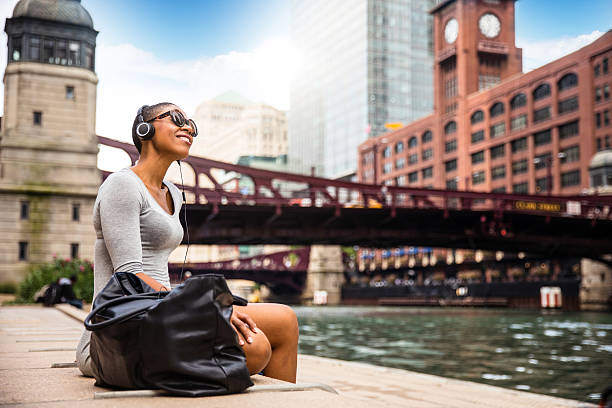 City break in Chicago - Woman relaxing at lunch time Woman in the city listening to music using wireless headphones. city break stock pictures, royalty-free photos & images